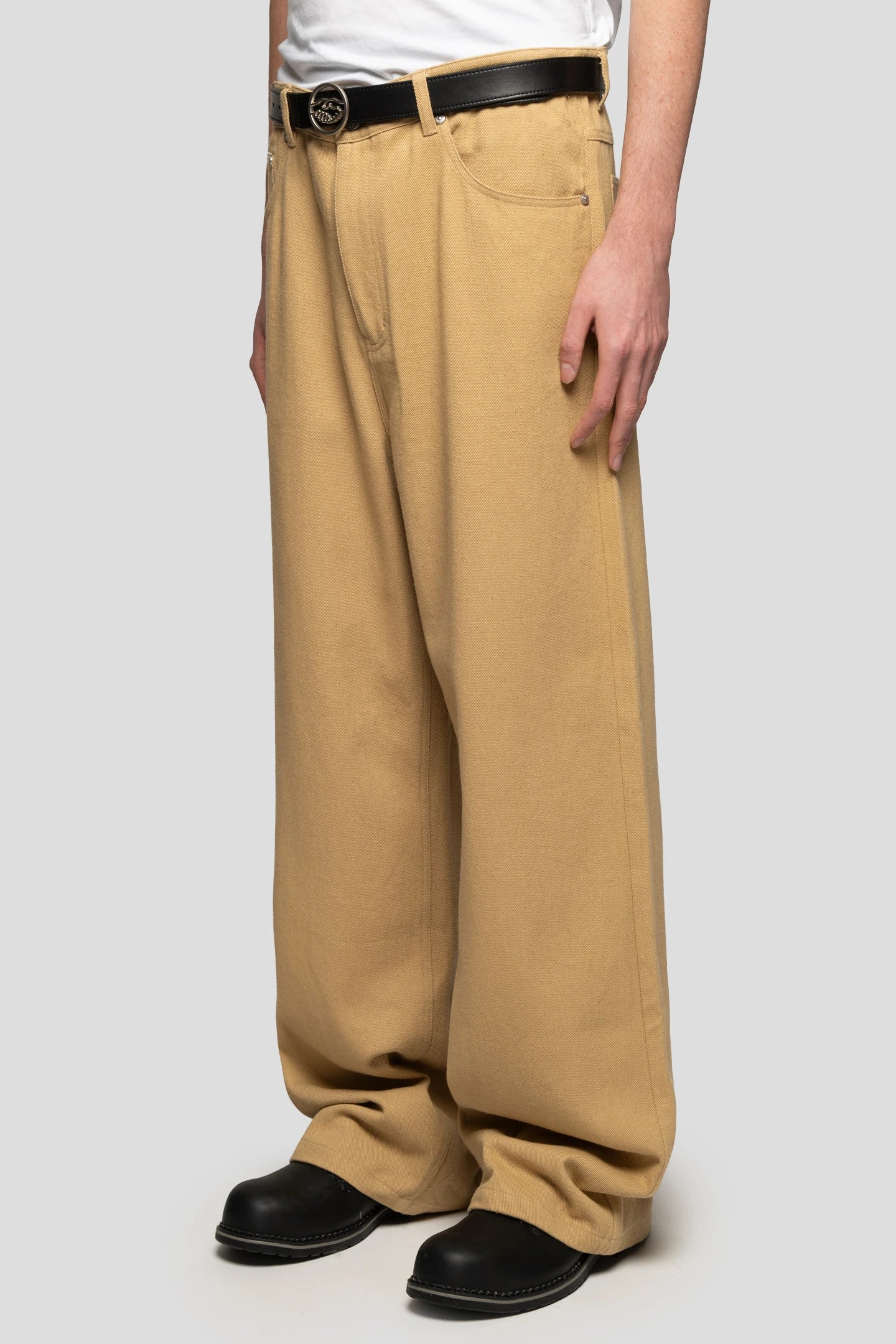 Model wearing beige baggy pants long cut with black belt by 93 sierra crosses