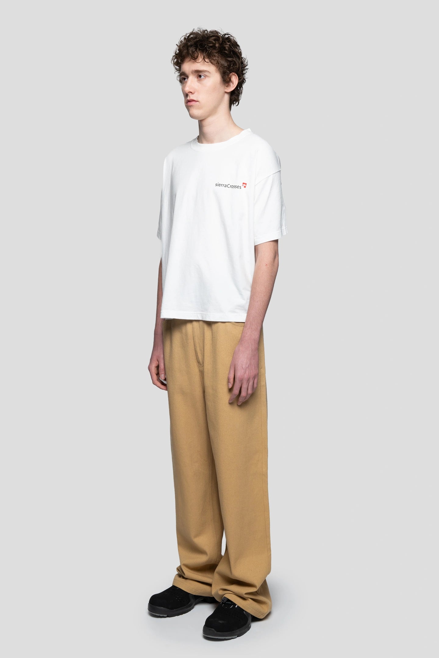 Modelo vistiendo una camiseta blanca con unos vaqueros color tierra
