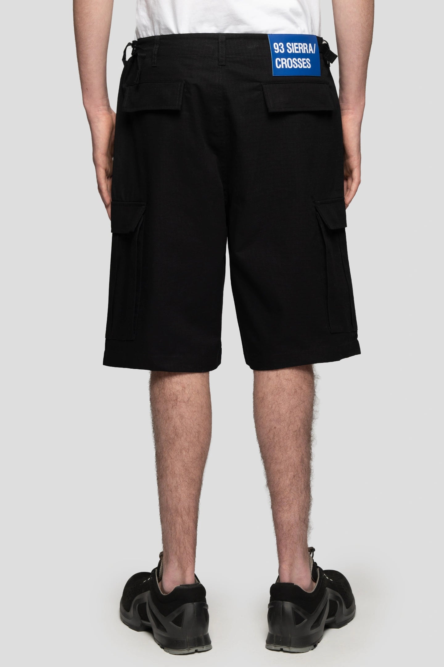 Model wearing black cargo shorts made out of ripstop durable cotton by 93 sierra crosses