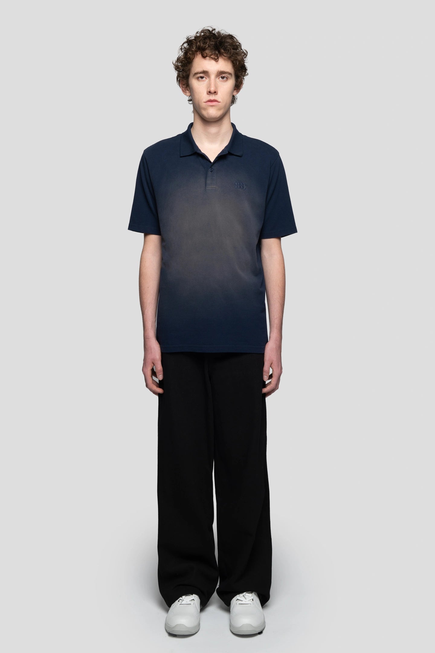 Front view model wearing faded print effect navy blue polo with black pants and working boots 93 sierra crosses
