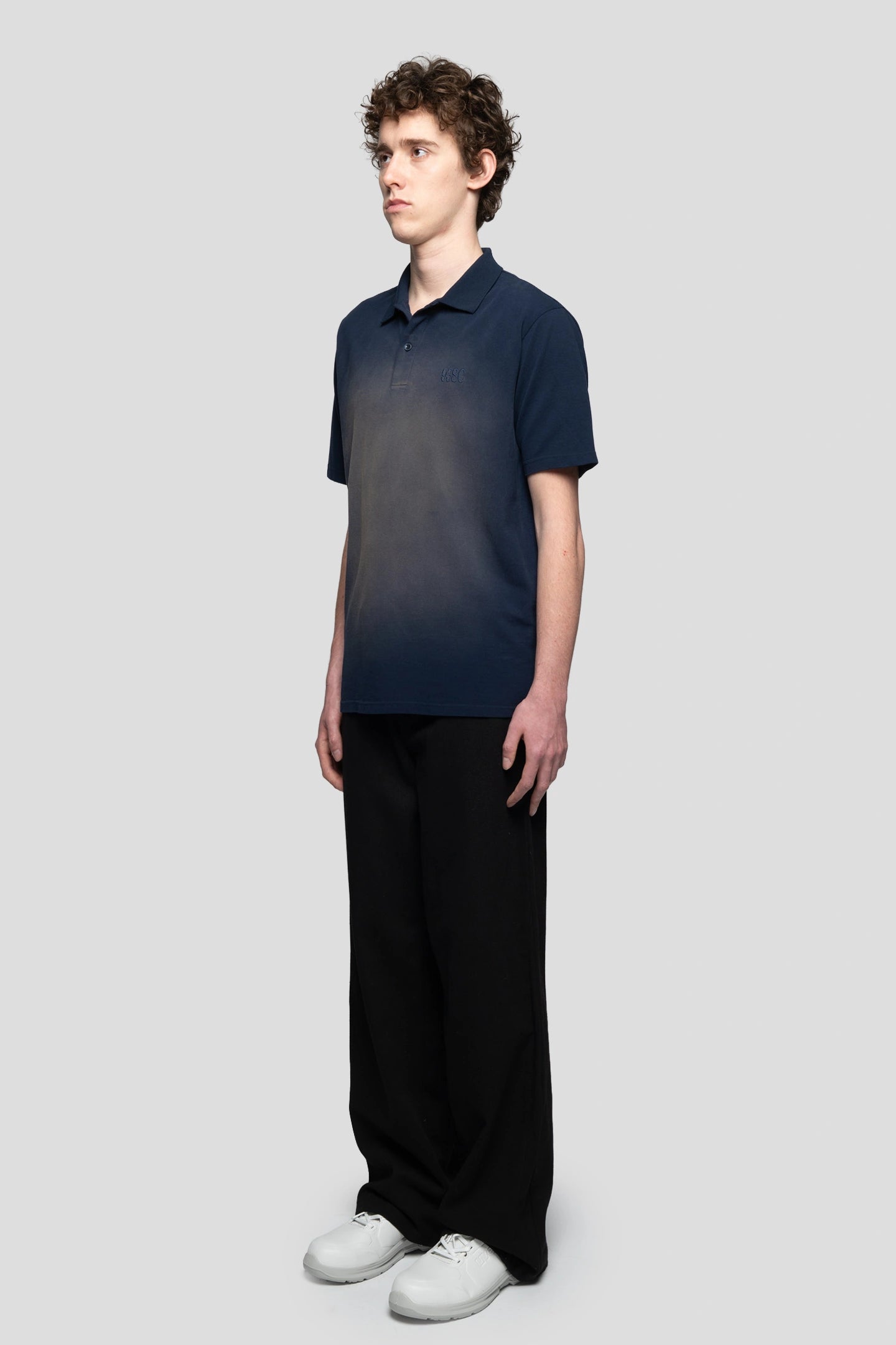 Model wearing navy blue polo with faded effect baggy pants and white boots 93 sierra crosses