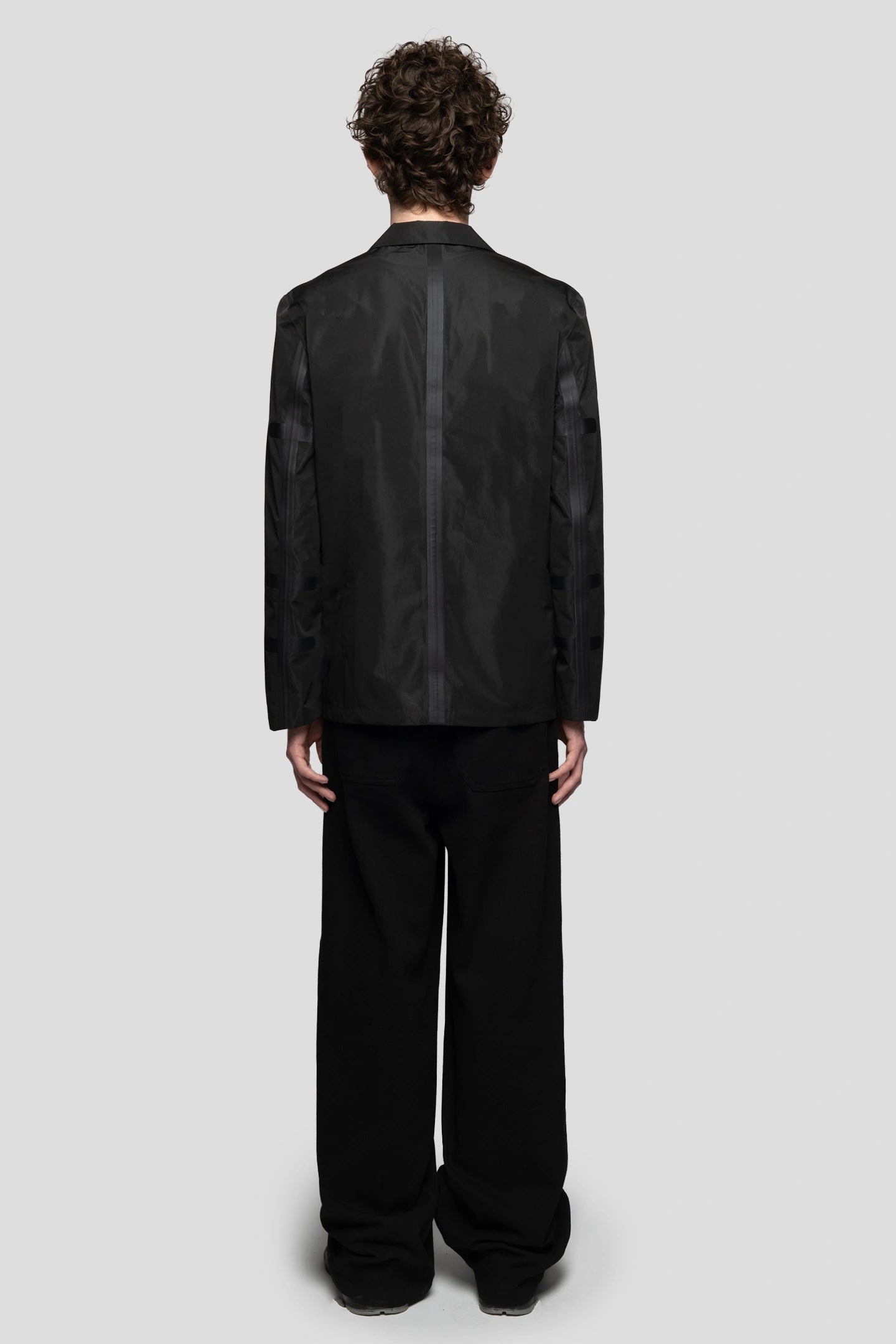 Back view of model wearing Triple Layer construction blazer for water resistance with black baggy pants 93 sierra crosses
