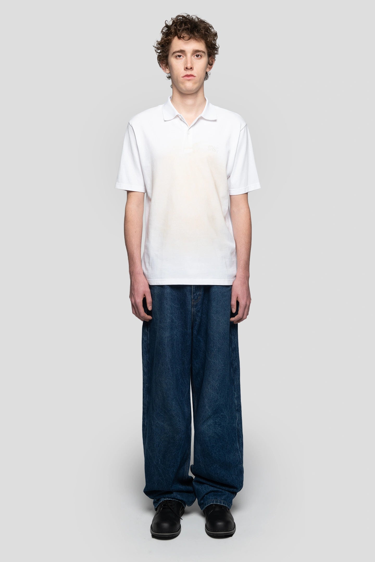 Front view of model wearing white polo with fake faded effect by 93 sierra crosses