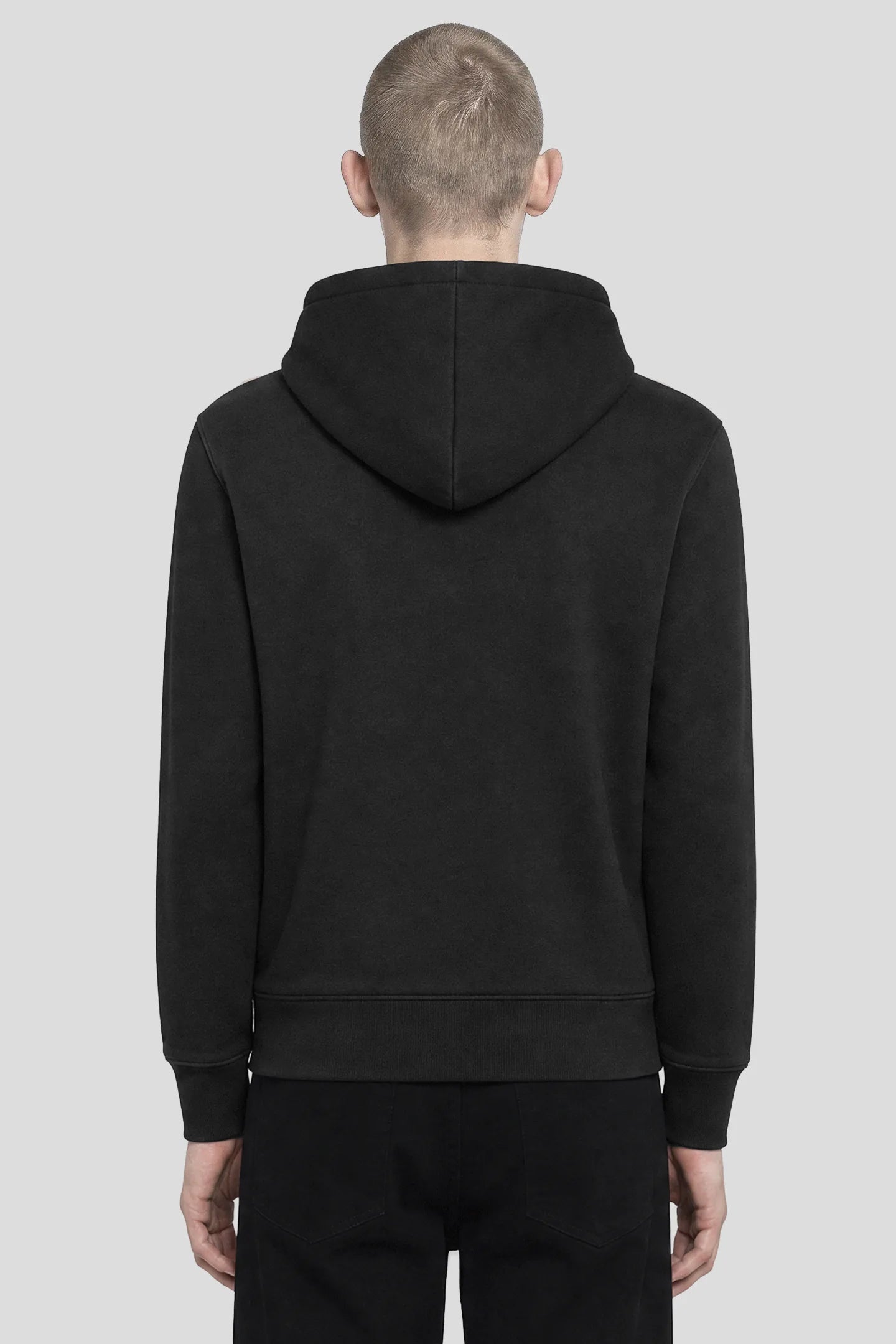 Back view of model wearing a plain black zip hoodie with ribbed cuffs and hem by 93 SIERRA/CROSSES