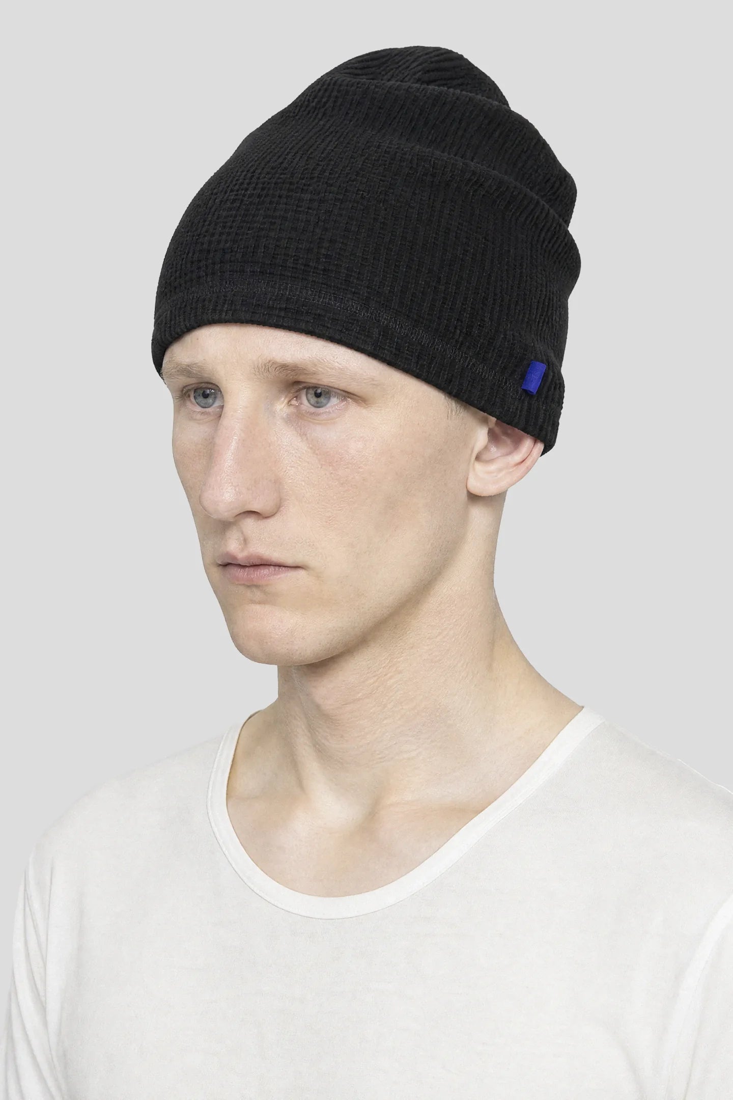Model wearing the Black Waffle Beanie with blue woven side tab by 93 SIERRA/CROSSES