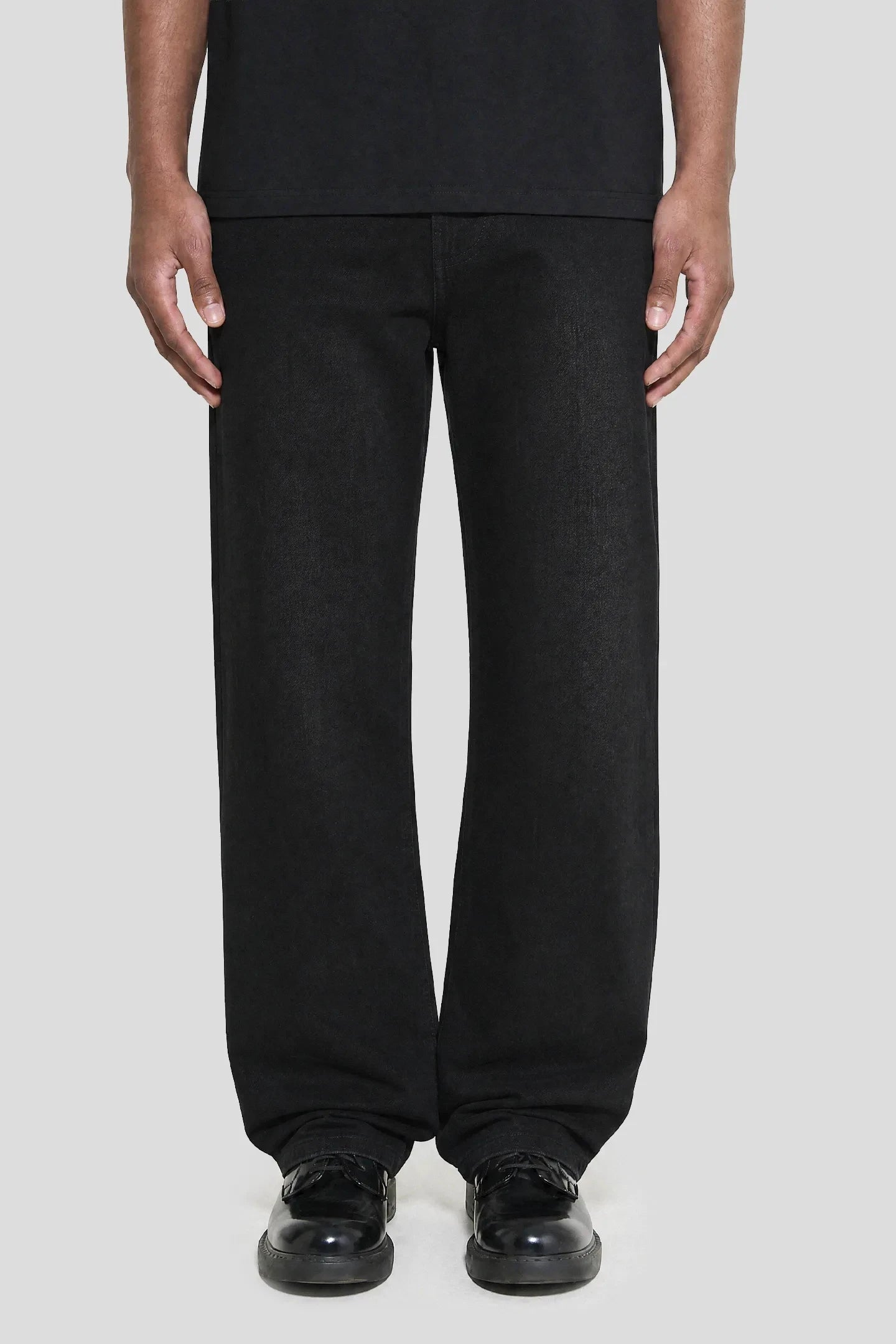 Model wearing the Regular Jeans - 001 in black wash with leather shoes, front view 93 SIERRA/CROSSES