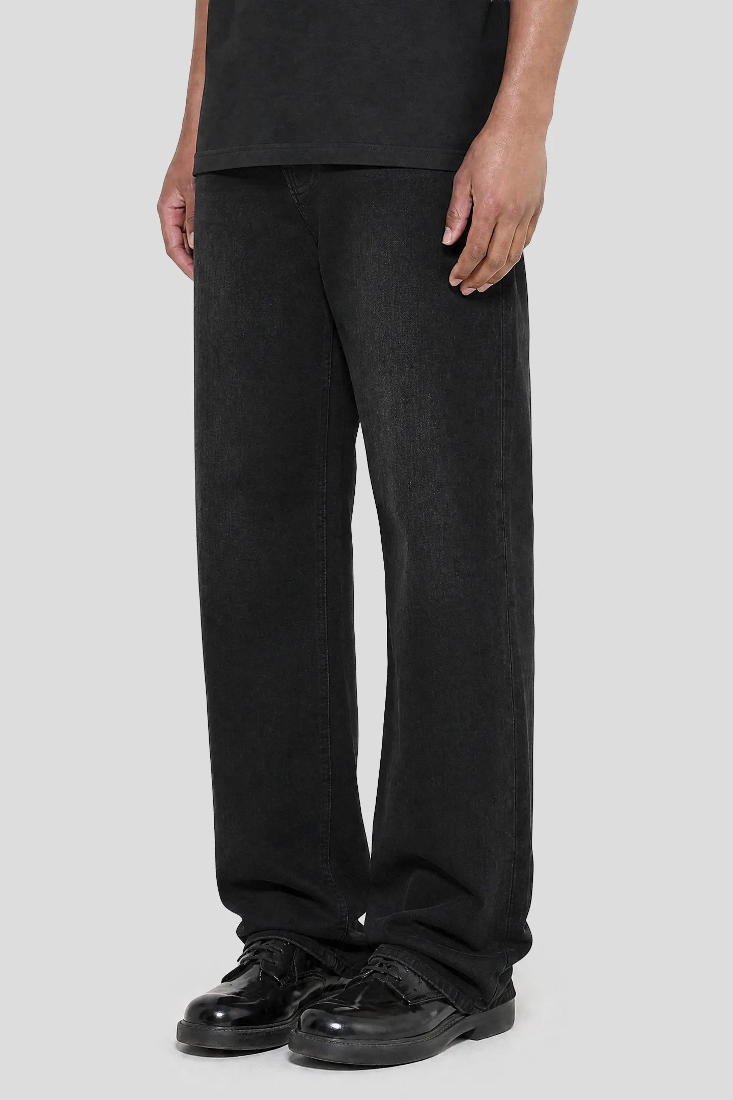 Model wearing the Regular Jeans - 001 in black wash with leather shoes, front view 93 SIERRA/CROSSES