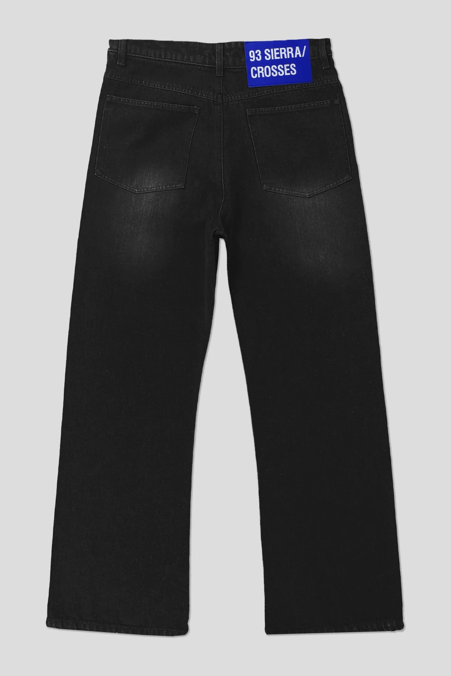 Black washed denim jeans with blue 93 SIERRA/CROSSES waistband label, product back view