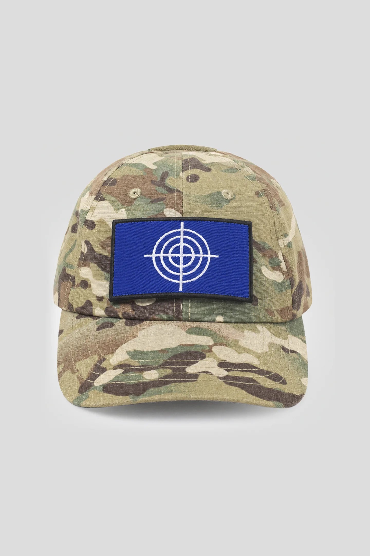 Model wearing the Crosshair Camo Hat, a camouflage cap with blue crosshair patch by 93 SIERRA/CROSSES