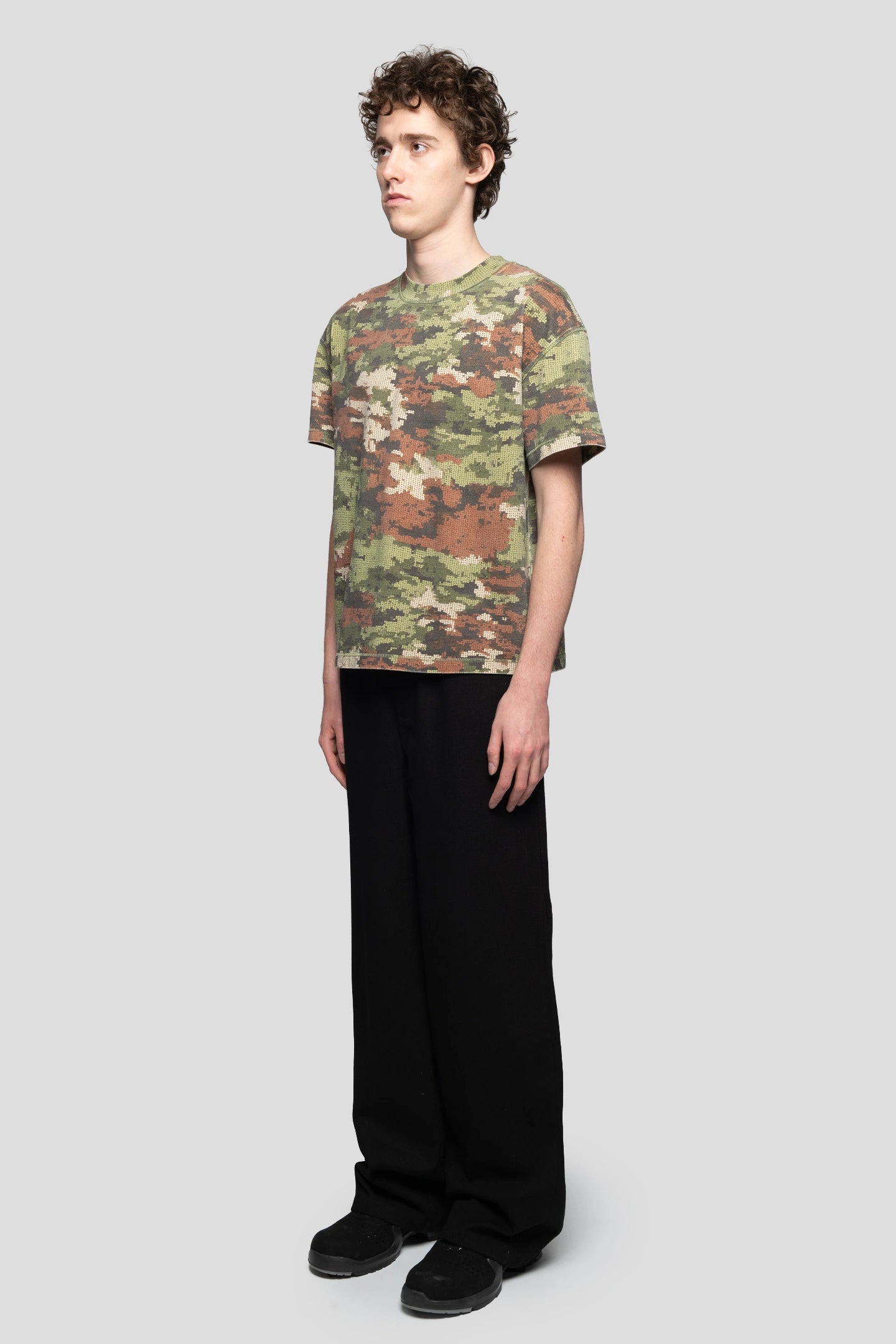 Diagonal view of model wearing regular fit digital camo t-shirt by 93 sierra crosses
