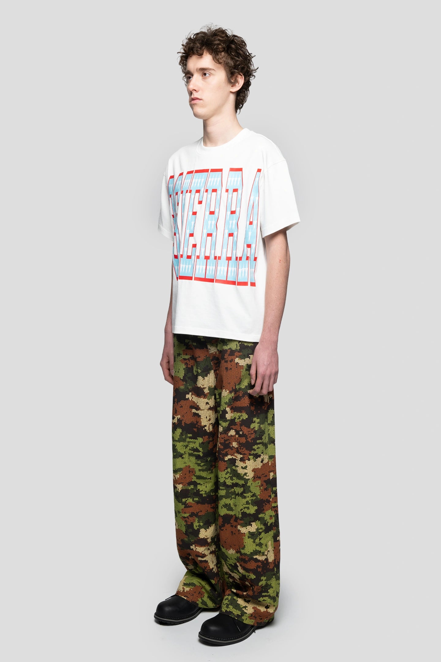 White oversized graphic t-shirt worn with camouflage pants in skater style”