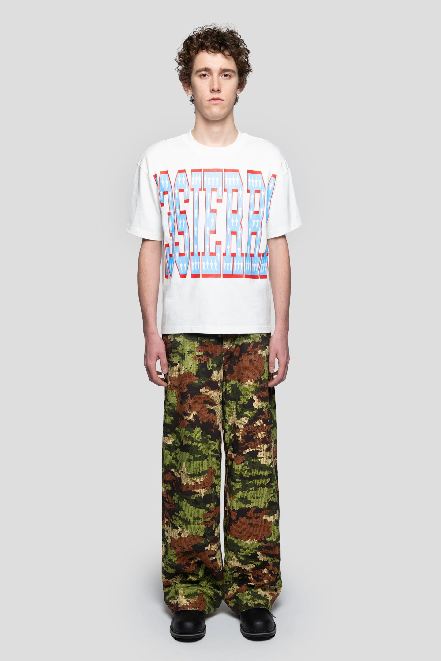 White oversized graphic t-shirt worn with camouflage pants in streetwear style
