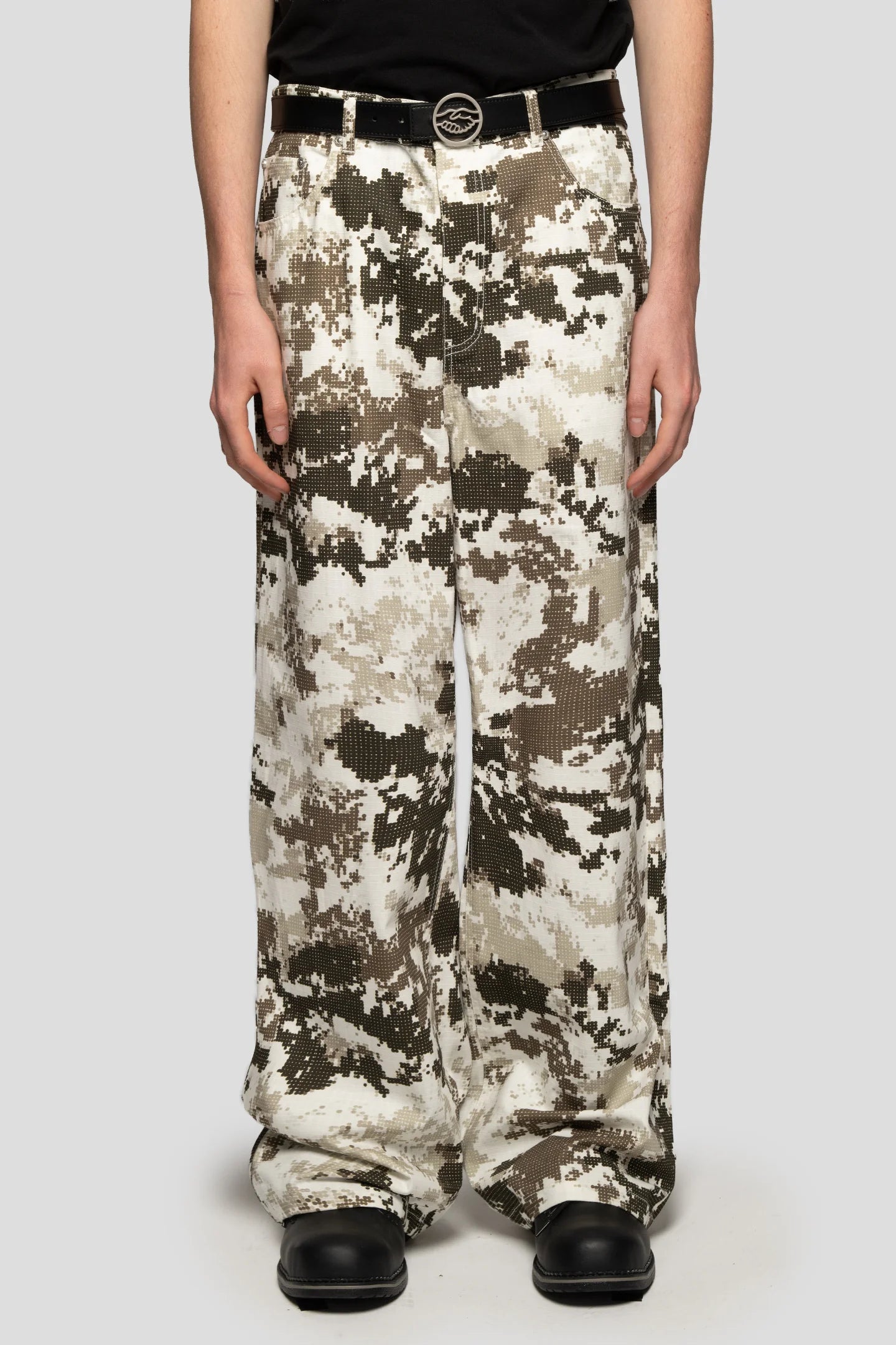front view of model wearing wide-leg digital camo trousers in beige and brown tones, relaxed streetwear fit by 93 Sierra Crosses